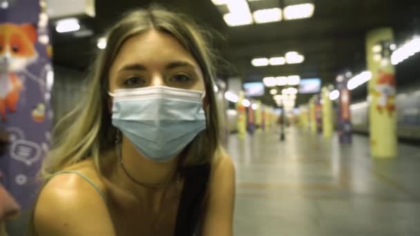 Chica en máscara médica a la espera de tren en el metro en la gran estación iluminada — Vídeos de Stock