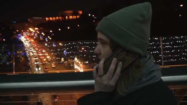 Menina falando ao telefone contra o fundo de uma grande cidade na noite de inverno — Vídeo de Stock