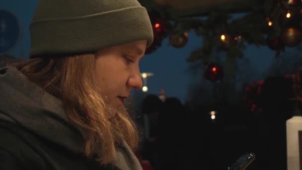 Девушка, ночью, зимой, на улице, во время заказа кофе и еды ждет встречи — стоковое видео