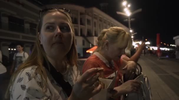 Ženy mají rádi koblihy s čokoládou, zatímco sedí na nábřeží města — Stock video