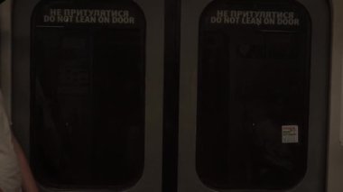 Tren tünelden geçiyor. Pencerelerde metro kapısı, bulanık lambalar uçuşuyor