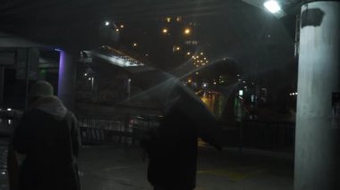 The guy and the girl had a fight in the city at night under the bridge in rain