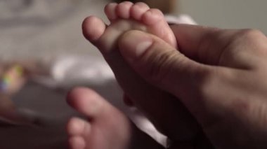 Yakın plan. Annem parmaklarıyla bebek topuğunu gıdıklıyor.
