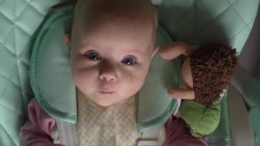 Çocuk ellerle oynadıktan sonra çocuk koltuğunda oturuyor.