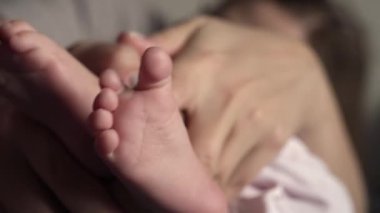 Yakın plan. Annem parmaklarıyla bebek topuğunu gıdıklıyor.