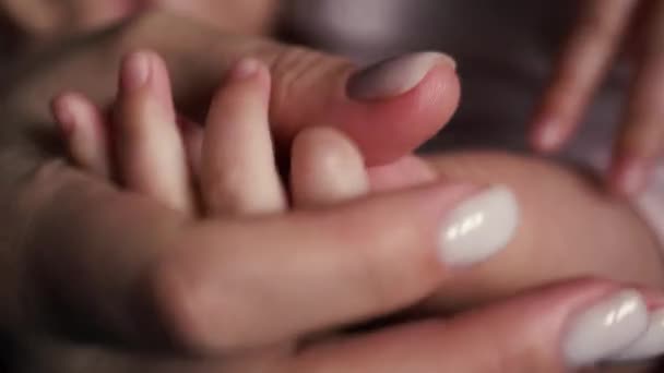 Baby knijpt moeders hand met kleine vingers. Close-up — Stockvideo