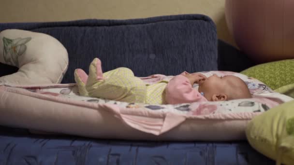 Emocionado pequeño bebé, en un traje de bebé, pone sus manos en su boca — Vídeo de stock