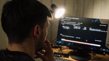 Hacker indirmeyi bekliyor. Program bilgisayarının kurulumunu bitir. Elektronik sigara içiyor. Duman, gece