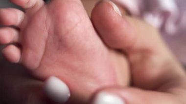 Yakın plan. Annem parmaklarıyla bebek topuğunu gıdıklıyor.