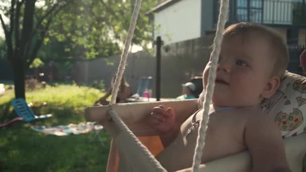 Daddy rides a little daughter on a swing. The child has a cross on his neck — Vídeo de Stock