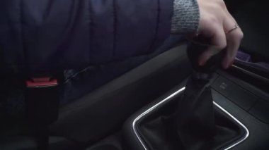 Kadınların elleri mekanik şanzıman değiştiriyor. Hızlanıyor, çukurların üzerinden geçiyor, çukurlar kazıyor. Kırmızı manikürlü tırnaklar, yüzük parmağı. Yakın plan. Emniyet kemeri, maske, telefon, anahtar, kot pantolon, ceket arka planı