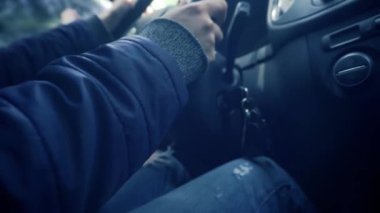 Araba kullanırken anahtarları kontakta sallamak. Kadınların elleri direksiyonu çevirir, manüel vitesi değiştirir pedallara ve debriyaja basar. Parmak yüzüğü, kot pantolon, ceket.