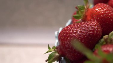 Panorama dolu, mavi sepet, tabak, vazo, konteyner, taze kırmızı, yeşil çilek mutfağı, gri, beyaz arka plan. Makro. Parlak çilek. Küçük taneler yeşil yapraklar kamerayı sağa çevirir