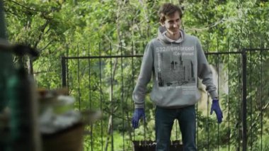 Gri kazaklı, tıbbi eldivenli bir adam arkası barbeküye dönük duruyor ve kendini ısıtıyor. El kol hareketi yapıp ellerini sallıyor, sonra da gidiyor. yaz, tatil, piknik