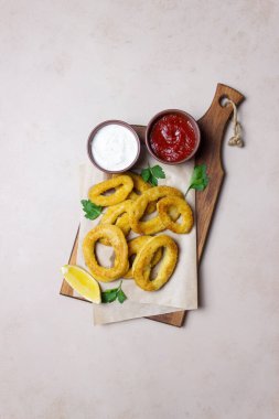 İki soslu kızarmış kalamar halkaları, limon ve otlar. Fast food. Aperatif