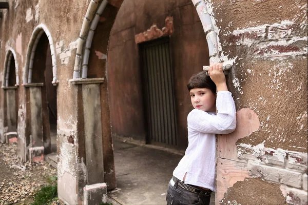 Маленькая симпатичная девочка-подросток с длинными темными волосами во дворе старого заброшенного дома 17 века — стоковое фото
