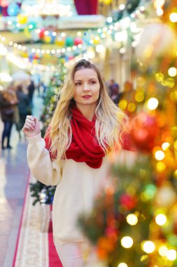 Kırmızı eşarplı mutlu sarışın kız dekore edilmiş Noel arkaplanındaki portreyi kapat.