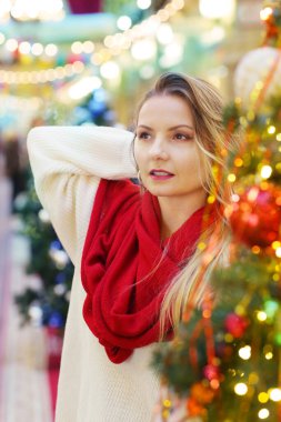 Kırmızı eşarplı mutlu sarışın kız dekore edilmiş Noel arkaplanındaki portreyi kapat.