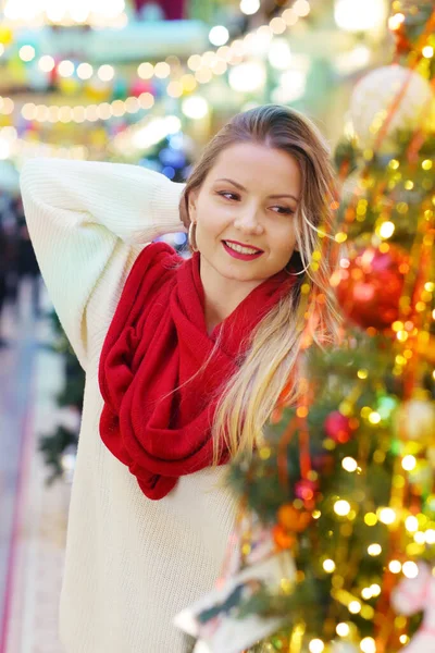 Kırmızı eşarplı mutlu sarışın kız dekore edilmiş Noel arkaplanındaki portreyi kapat.