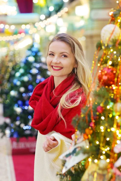 Kırmızı eşarplı mutlu sarışın kız dekore edilmiş Noel arkaplanındaki portreyi kapat.