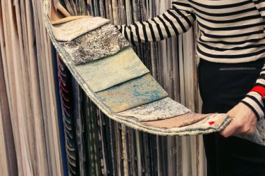 Kadın eli pencere tasarımı için perde ve aksesuar örnekleri seçiyor. Fotoğrafı kapat.