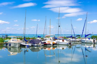 Yatlar turkuaz suyla dolu bir gölün kıyısına demirlenir..