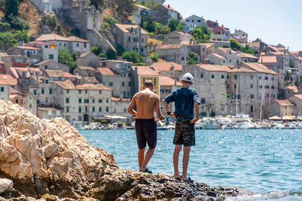 Sibenik Croatia, two young fishermen on the background of the city
