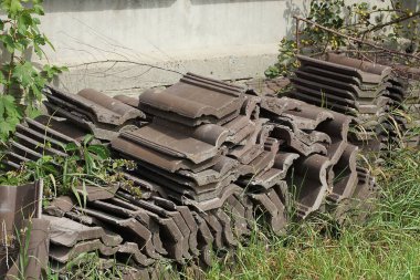 Dışarıda yeşil çimenlikte büyük bir yığın eski kahverengi fayans var.