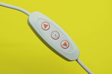 Sarı arka planda kırmızı düğmeli beyaz plastik bir anahtar.