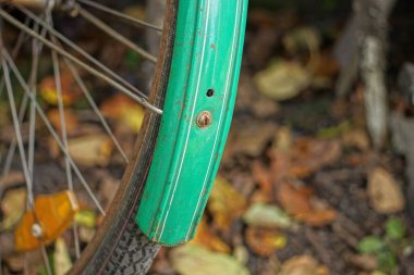 Siyah bisiklet tekerleğinde yeşil metal bisiklet çamurluğu ve yolda gri demir teller.