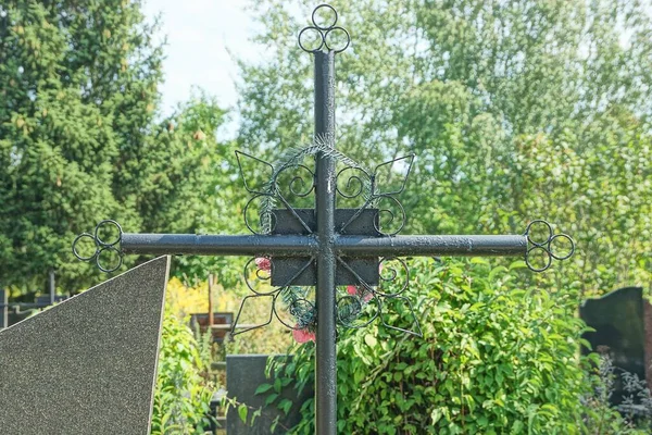Uma Cruz Metal Preto Uma Sepultura Cemitério Coberto Vegetação Verde — Fotografia de Stock