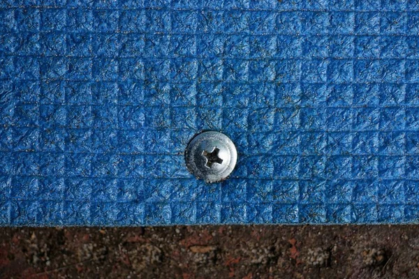 Один Серый Металлический Винт Вкрученный Синий Кусок Пластика Коричневой Стене — стоковое фото