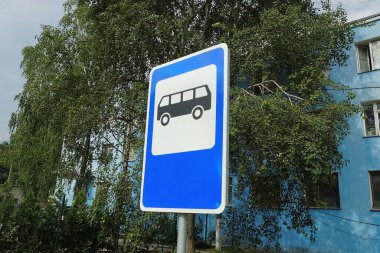 Yeşil bitki örtüsü ve gökyüzü üzerinde bir yol tabelası otobüs durağı