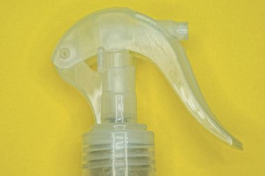 Antiseptik şişenin üzerinde beyaz bir plastik sprey sprey şişesi sarı masanın üzerinde duruyor.