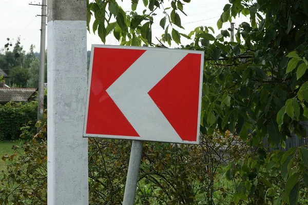 Een Verkeersbord Draaien Richting Met Rode Witte Pijlen Groene Vegetatie — Stockfoto