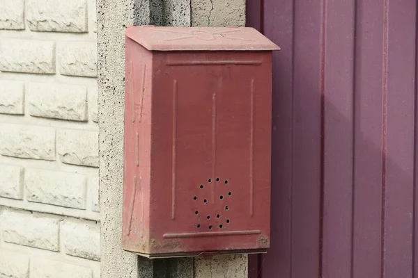 一个红色的金属信箱挂在街上篱笆的白色砖墙上 — 图库照片