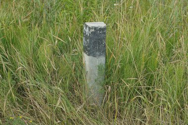 Yeşil çimlerin üzerinde gri bir sınır karakolu var.