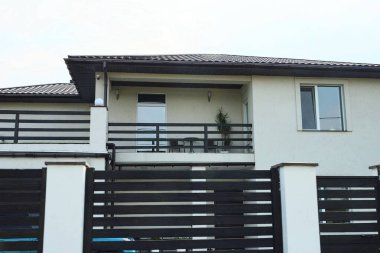 Özel bir evin gri duvarında açık siyah ahşap bir balkon.