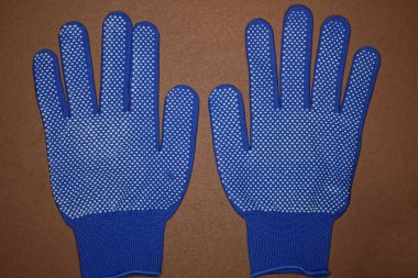 Mavi beyaz kumaştan yapılmış iki yeni iş eldiveni kahverengi bir masada yatıyor.