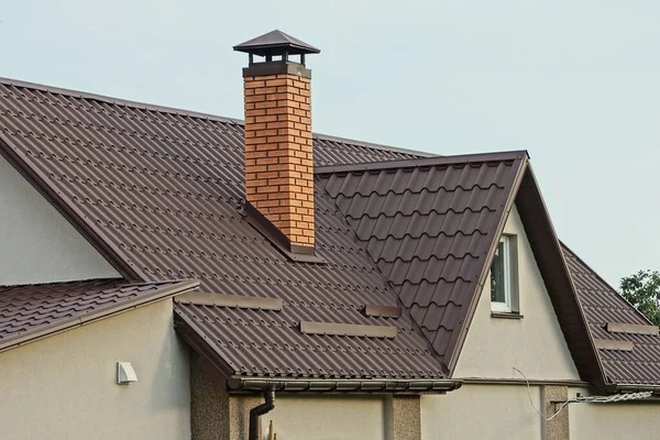 プライベートグレーの家の茶色のタイル張りの屋根の上に赤い大きな煙突が1つ空に向かって窓がある — ストック写真