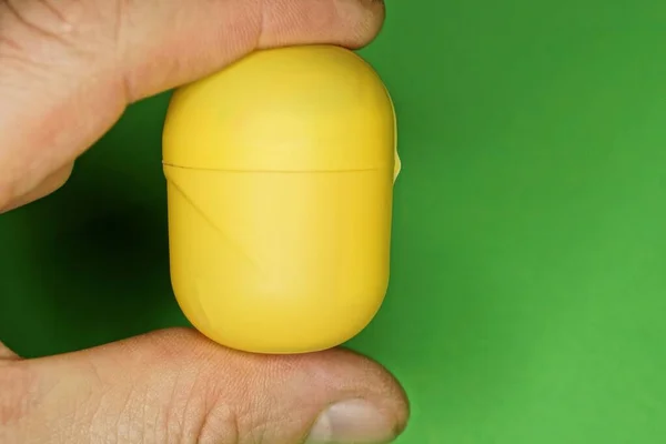 Пальцы Держат Одну Овальную Желтую Пластиковую Коробку Зеленом Фоне — стоковое фото