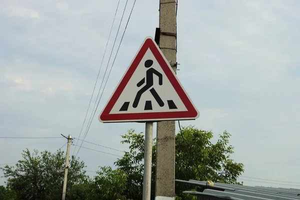 灰色の空を背景に柱の上を横断する三角形の道路標識が — ストック写真