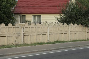 Asfalt yolda uzun, gri beton bir duvar var.