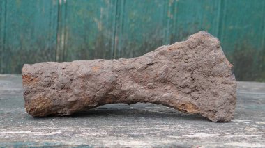 Yeşil duvardaki gri tahtada eski kahverengi paslı bir balta.