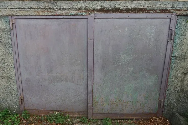 通りのガレージの灰色のコンクリートの壁にある古いバイオレット鉄の門 — ストック写真