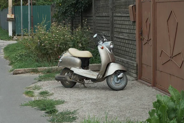 一辆灰色的摩托车停在街上的柏油路上 停在篱笆墙边的绿草上 — 图库照片