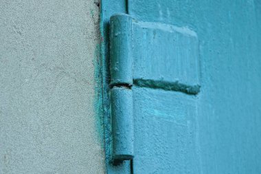 Gri beton duvarda bir yeşil demir kapı menteşesi