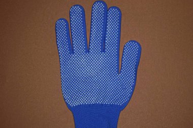 Mavi beyaz kumaştan yapılmış yeni bir iş eldiveni kahverengi bir masada yatıyor.