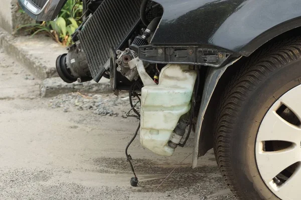 道路上の灰色のアスファルトの道路上に黒い車輪の部品と油のための白いプラスチック製のタンクを有する分解乗用車の一部 — ストック写真