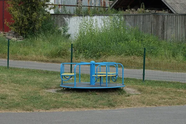 孩子们的游乐场 地面上有一个圆形的蓝色旋转木马 街上有绿草 — 图库照片